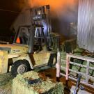 Forklift pulls hay from the fire.