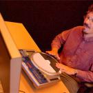 photo: man at computerized drum machine in front of a computer