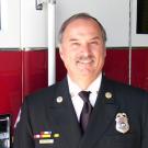 Fire chief in uniform, in front of UC Davis firetruck