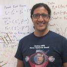 Man stands in front of whiteboard filled with calculations.