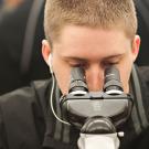 A male student looks into a piece of scientific equipment