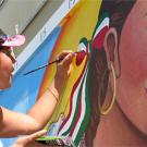 Photo: Maria Alvarado painting on a wall