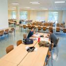 Two students sit in wide open room filled with new desk and new chairs, in new study space in Shields Library.