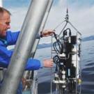 Photo: man lowers equipment from boat into lake