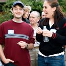 Photo: Group of people: guy looking at camera, woman laughing, looking at him, three older people behind