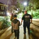 Police officers and two others walk along a campus path at night.