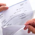 Hands pull paper paycheck from envelope.