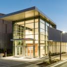 Building exterior in the evening, with lights shining from inside glass-walled lobby 