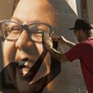 Photo: Photo: Unidentified worker casts a shadow on poster (Angel Hinzo) as he installs it.