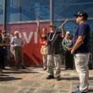 Man performs Indioan blessing while holding a clapper (stick) and feathers, in front of new historical marker.