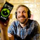 Man in earphones holding an electronic device with a lit green circle in the middle