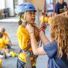 Wall-climbing class: Adult buckles girl's helmet.