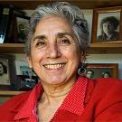 Photo: Brenda Deen Schildgen with photographs on shelves behind her.