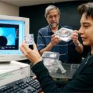 Graduate student Maria Ferrua looks at marbles used to model the air flow around objects, like different types of fruit. R. Paul Singh is shown holding  strawberry cartons that are currently available commercially. He is using computer models to