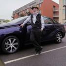 Male scientist stands with hydrogen fuel cell vehicle