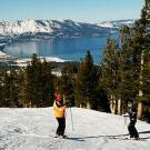 Photo: skiers on slope with Tahoe in the distance