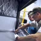 Two men inspecting an air conditioner