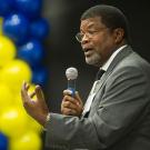 Walter Robinson with microphone, with blue-and-gold balloons in background