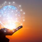 A lighted globe in a hand against sunset