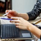 Closeup of two people pointing at laptop screen