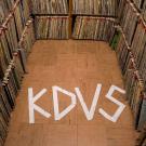 Photo: stacks of records with KDVS spelled on the floor with tape