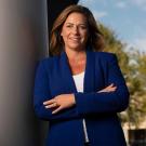Jonna Mazet leans against a wall while wearing a blue blazer