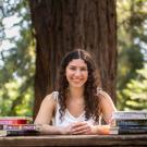 Woman at park table behind stacks of books