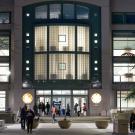 students moving in and out of library on UC Davis campus at night with light pouring through windows.