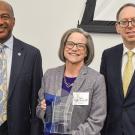 Three people pose for a photo with an award