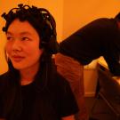 Student sits with EEG equipment on her head in a room lit with amber light