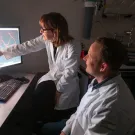 Photo of two scientists looking at a screen with logo superimposed: From Labs to Lives