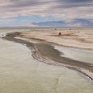 drone image of Salton Sea waters going up to dry lakebed with mountains in distance