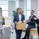 Workers convene in office, one with box