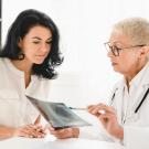 Senior doctor general practitioner showing x-ray lungs photo to female patient