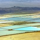 Aerial view of a desert landscape with bright blue squares in the center. 