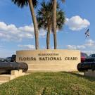 Photo of National Guard headquarters in Florida showing cement building, palm trees and blue sky