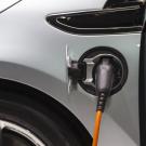 Electric vehicle plugged in and charging, gray