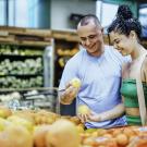 Couple of people in grocery store looking at produce 