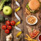 Low-fat veggies and fruits like broccoli, apples, tomatoes shown on left and high-fat foods like hamburgers, pizza and french fries on the right. A tape measure divides the two sides. UC Davis researchers find that switching from a high-fat to a low-fat diet slowed precancerous changes in the pancreas of mice. (Getty)