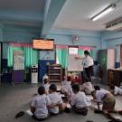 Girl in a brown patterned shirt and white pants sits down in front of a view of the Golden Gate bridge in San Francisco. 