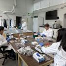 Foundation Plant Services technicians in white lab coats at table processing grapevine material in plastic bags from the Classic Foundation Vineyard. (Foundation Plant Services / UC Davis)