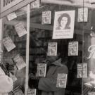 Black and white photo of woman looking in bookstore window of her own book