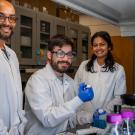 Three researchers in lab coats smile for the camera