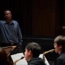 Black man standing and directing band members