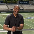 With the football field in the background, Ron Austin leans against the top rail of seating at UC Davis Health Stadium