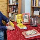Man in blue plaid jacket signs books at bookstore table