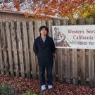 Seito Ezawa poses next to a sign for the Western Service Workers Association