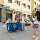 A man and a woman photograph a student with belongings in front of Shasta Hall