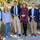Six people pose for photo. Three of them hold awards.