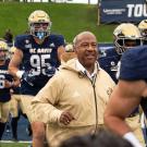 Chancellor Gary S. May runs next to many football players